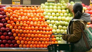 A woman shops for fruit at a grocery store.