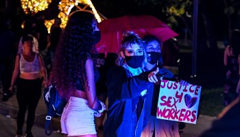 Activists and sex workers hold up signs near police as they participate in a "Slut Walk" in Miami Beach, Florida, on December 5, 2020.