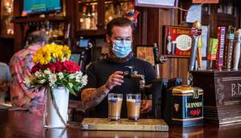 A bartender pours drinks while wearing a mask in Austin, Texas.
