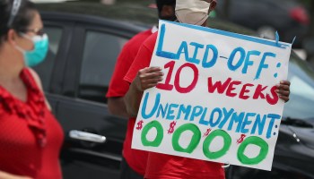 A protester holds up a sign reading, "Laid-off: 10 weeks. Unemployment: $0."