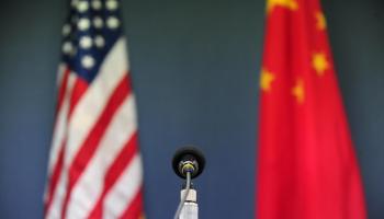 A U.S. and China flag are behind a microphone.