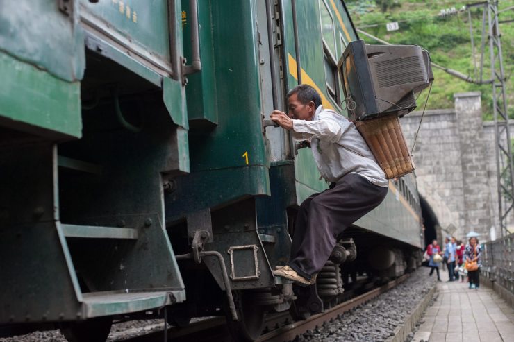 A villager boards a slow train with a television strapped to his back in 2015. The train connected communities in Sichuan and Yunnan provinces that were not frequently served by China's modernized rail network.