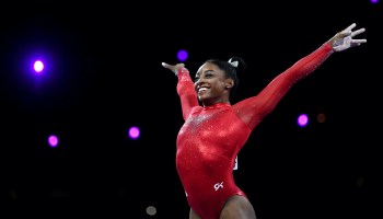 Gymnast Simone Biles sticks the landing at the end of a vault competition routine in 2019.