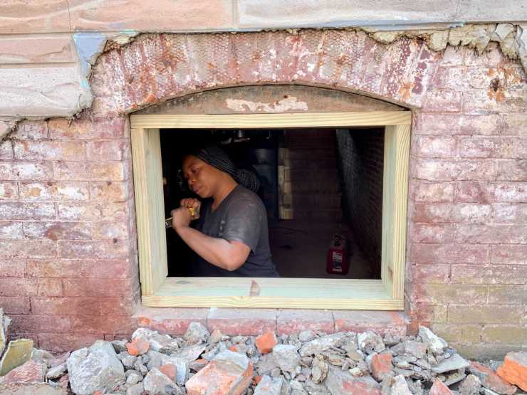 Bryanna Vellines, 28, installs a window frame in an old Baltimore row house.