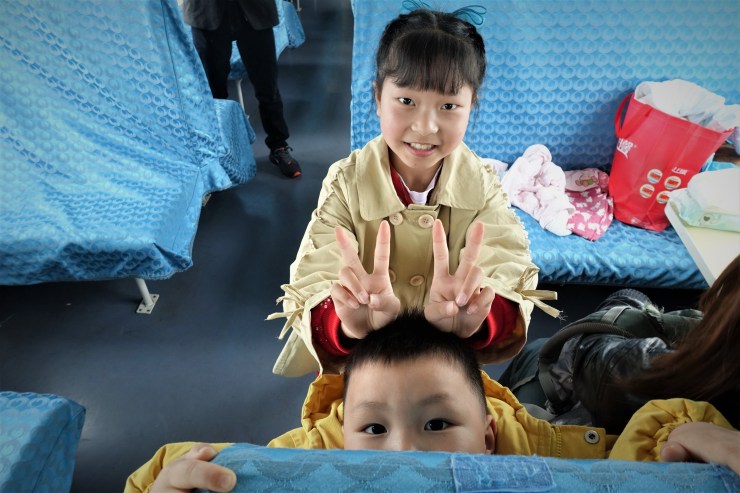 Chang Yuanhong's son (bottom) plays with a fellow train passenger. He is among the lucky ones who is growing up with both of his parents by his side. (Charles Zhang/Marketplace)