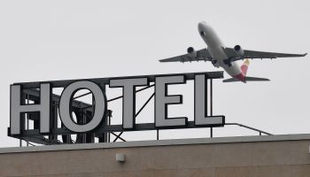 An airplane flies over a hotel sign in London. As travel demand bounces back, Kurt Loudenback, CEO of a company that makes hotel breakfast food, is optimistic that his business will return to pre-pandemic levels.