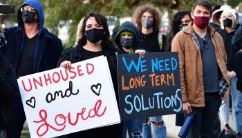 Activists, advocates and those experiencing homelessness rally holding sings that read "Unhoused and Loved" and "We need long-term solutions" at Echo Lake Park in Los Angeles, California.