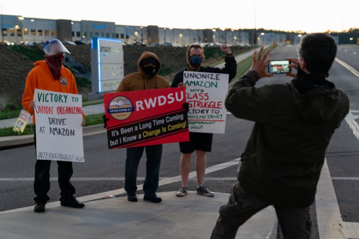 A supporter of the RWDSU unionization effort takes a photo of the RWDSU union rep standing with other supporters outside the Amazon fulfillment warehouse at the center of a unionization drive on March 29, 2021.