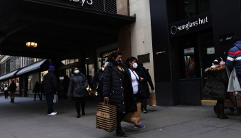 People carry shopping bags as they walk down 34th Street on February 26, 2021 in Midtown Manhattan in New York City.