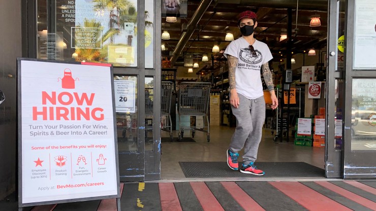 A customer walks by a "Now Hiring" sign at a BevMo store on April 2, 2021 in Larkspur, California.