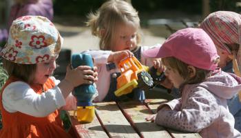 A group of toddlers plays with toy trucks.