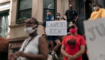 A group of housing activists gathered on a stoop, with one sign reading "Cancel Rent."