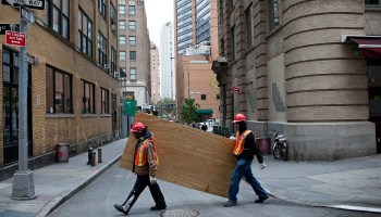 Two construction workers carrying a large piece of wood.