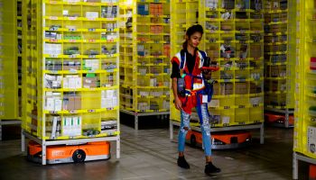 A woman walks through yellow warehouse shelves.