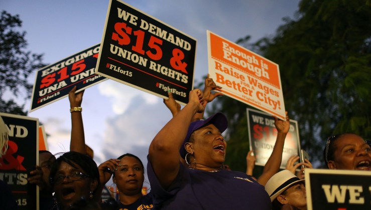 Protesters hold signs demanding a $15 an hour minimum wage.