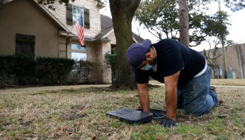 A plumber works in the front yard of a Houston home.