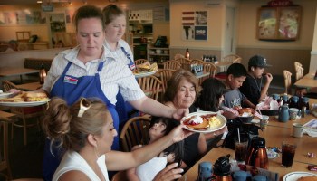 Two waitresses serve a family pancakes at an IHOP.