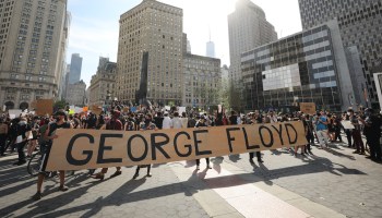 Protesters gather with a sign reading "GEORGE FLOYD."