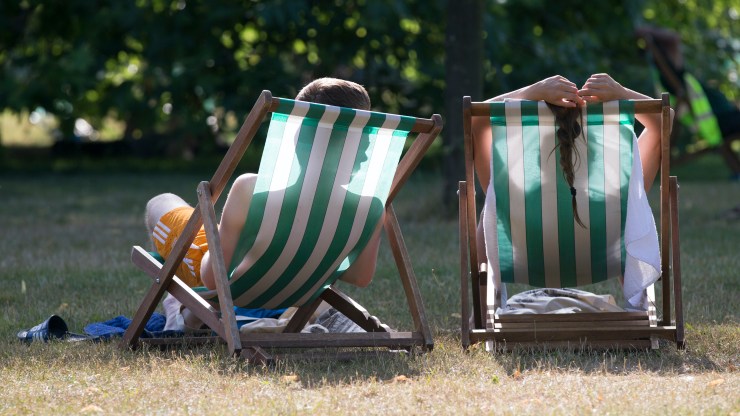 A couple sits in deck chairs. Employers might receive a wave of employee time off requests in the near future, testing companies' flexibility.