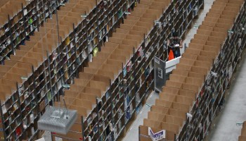 A worker sorts through shelves of inventory at an Amazon warehouse.