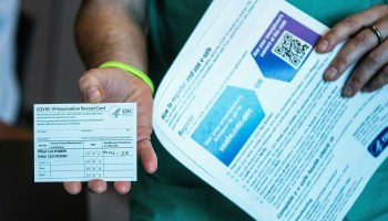 A person holds up their COVID-19 vaccination card after receiving a dose of the Pfizer-BioNTech vaccine.