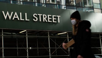 A woman walks past a sign reading "Wall Street" in New York on February 8, 2021.