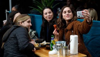 Restaurant customers take a photograph together while eating and drinking together outside in the Soho area of London.