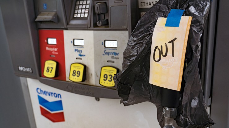 A pump at a gas station is covered by a black plastic bag and a sign that reads "Out" as drivers rush to fill up their tanks over fears of short supply.