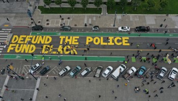 Protesters paint a mural on the street that says "defund the police."