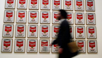 A museum visitor walks by Andy Warhol's "Campbell's Soup Cans."