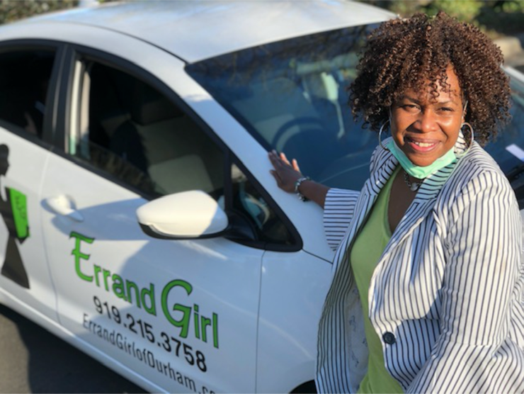 Tina Travis, founder of Errand Girl of Durham, stands next to a car reading "Errand Girl."