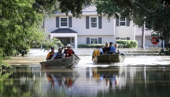 Residents in a flooded neighborhood take rafts back to their homes.