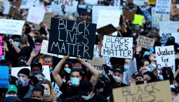 Protesters hold Black Lives Matter signs.
