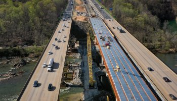 An aerial view of vehicles on a highway passing an expansion project.