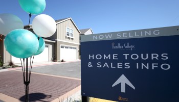 A sign advertises home tours and sales at a housing development.