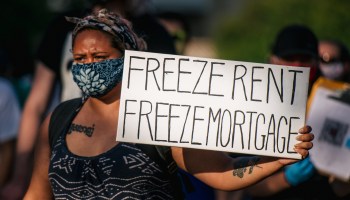 A woman holds a sign saying, "Freeze rent Freeze mortgage"