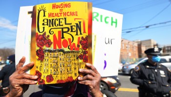 A woman holds up a "Cancel Rent" sign.