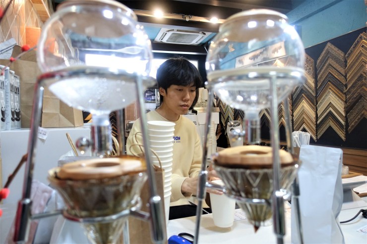 Nameless Coffee barista Liu Yi seen with ice-drip coffee machines, which take six to eight hours to produce one cup (Charles Zhang/Marketplace)
