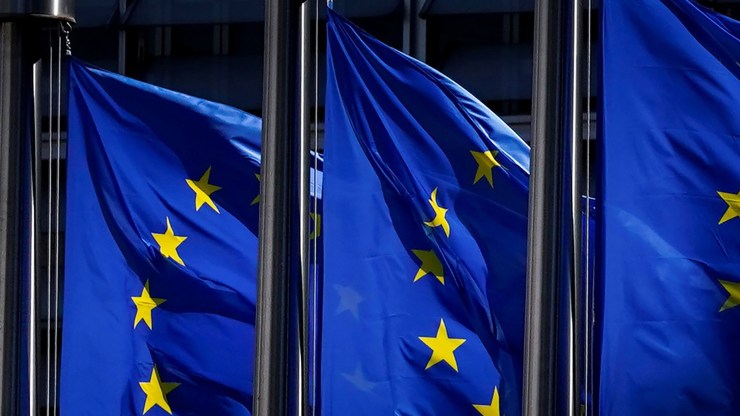 This combination of file pictures shows the European Union flags outside the European Commission building in Brussels in May 2020.