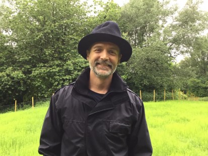 Patrick Grant poses for a photo in a field. 