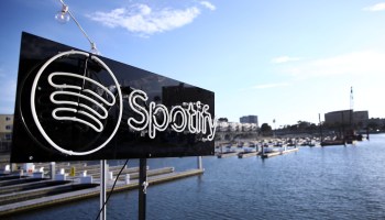 A Spotify sign in front of a body of water with boats in it.