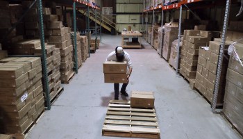 A worker moves boxes in a warehouse.