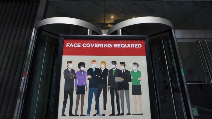 A sign outside of an office building in New York reads "Face Covering Required."