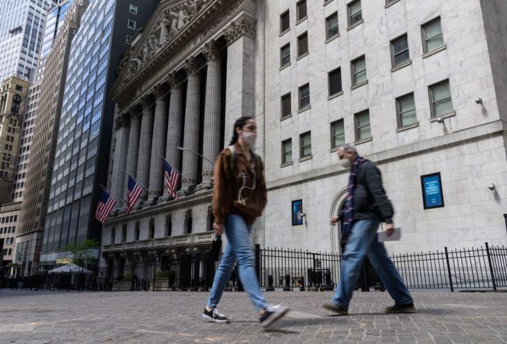 People walk past the New York Stock Exchange on Wall Street.