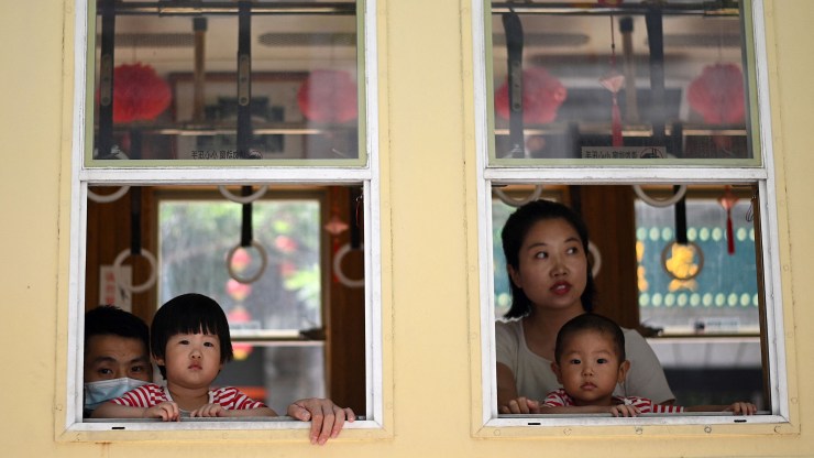 Children peek out from a window with their parents along Qianmen Street, a popular touris, and shopping area, on International Children's Day in Beijing on June 1, 2021.