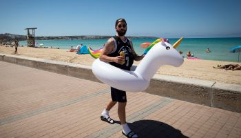 A man walks with a unicorn water float at Palma Beach in Palma de Mallorca, Spain, on June 7, 2021.