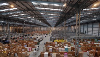 An overview of a large warehouse filled with thousands of boxes and a handful of workers.
