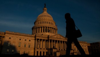 A person walks past the United States Capitol at dusk.