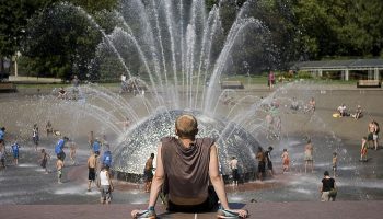 A man tries to beat the heat while sitting in front of a Seattle fountain.