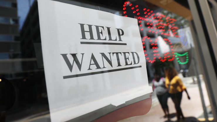 A shop displays a help wanted sign.